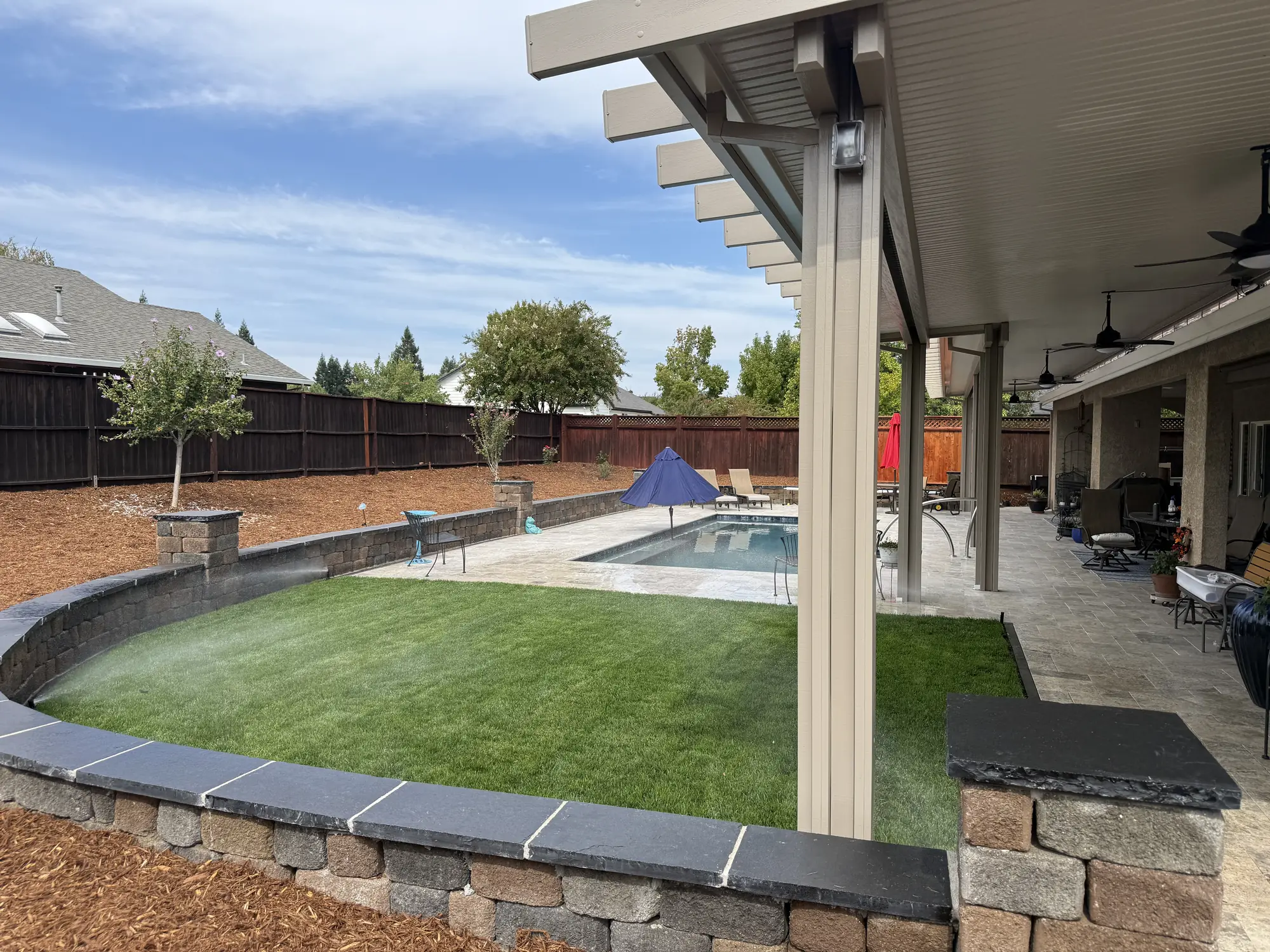 Curved block wall around a new lawn beside a backyard pool