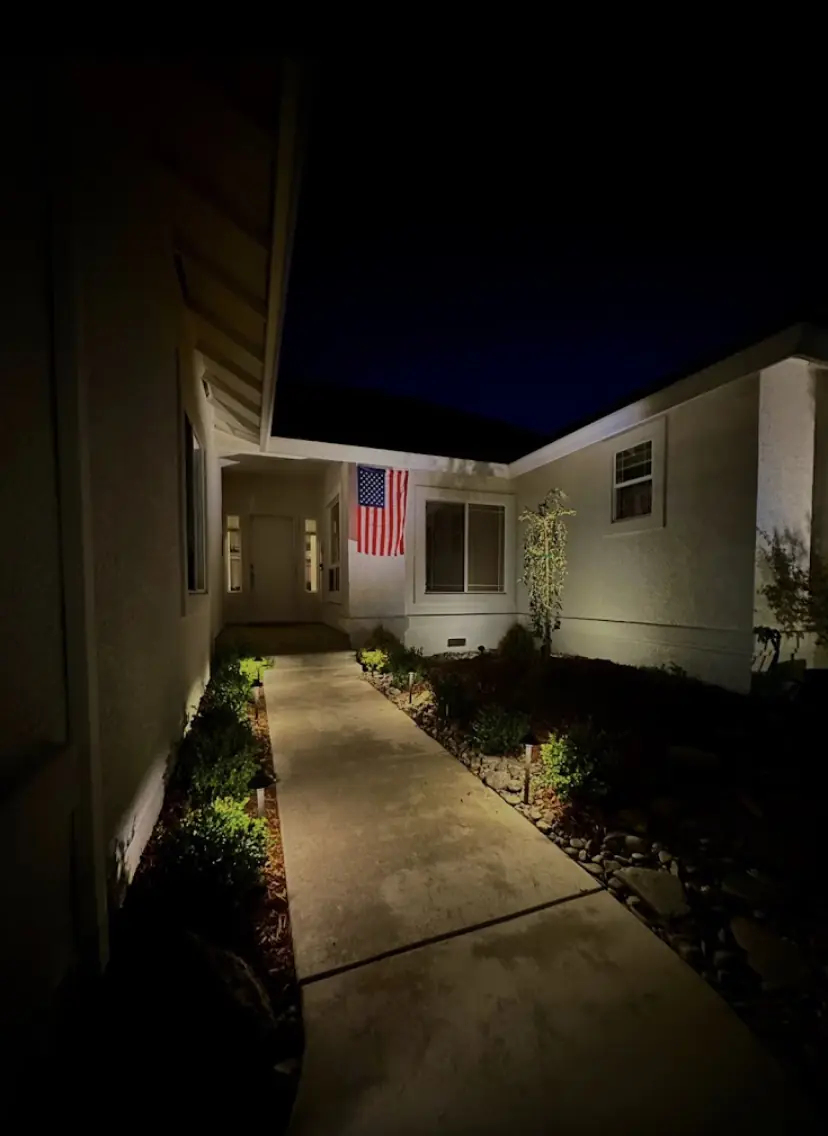 Walkway to a front door lined with path lights at night