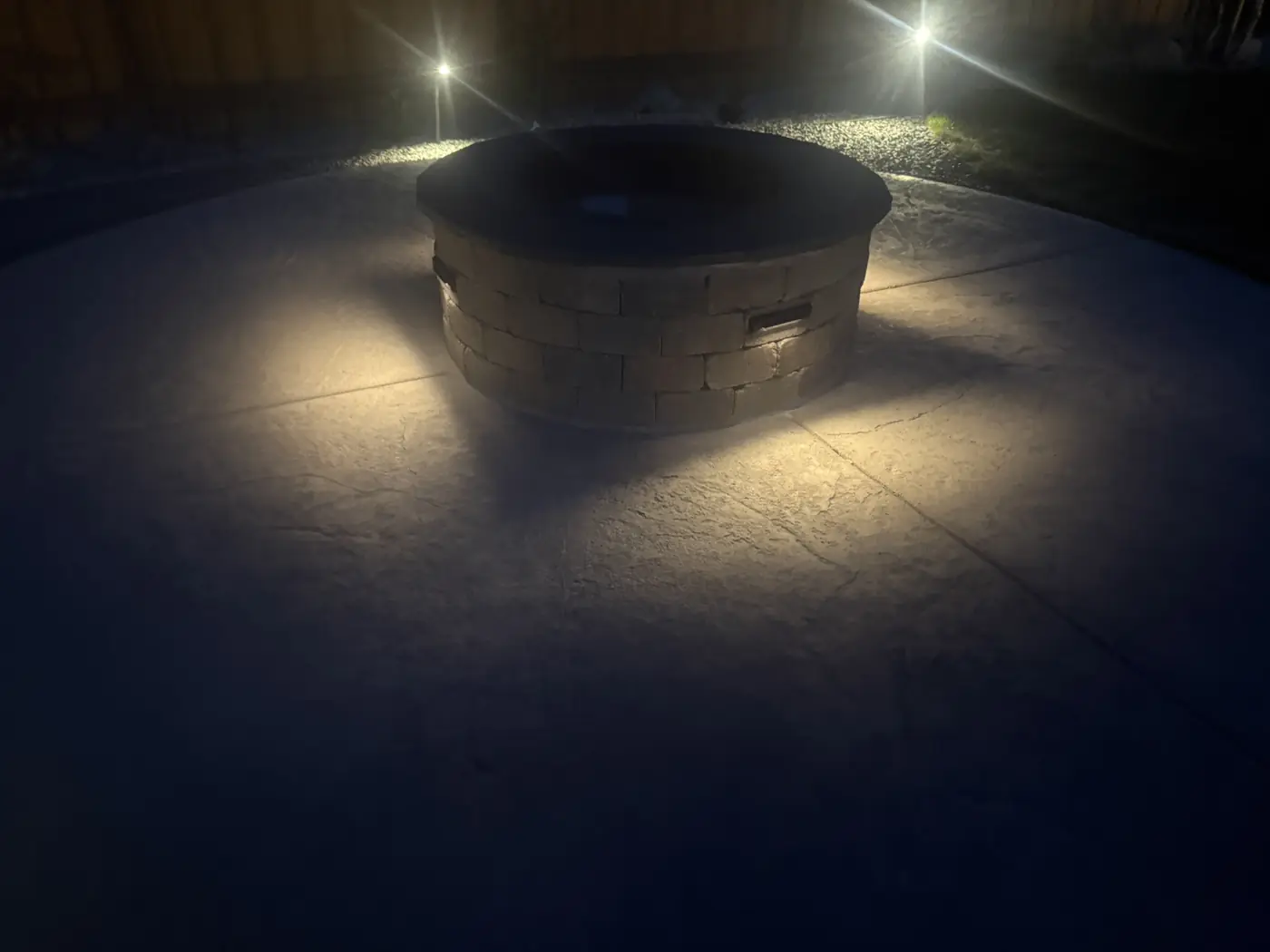 Stone fire pit lit by low voltage lights at night