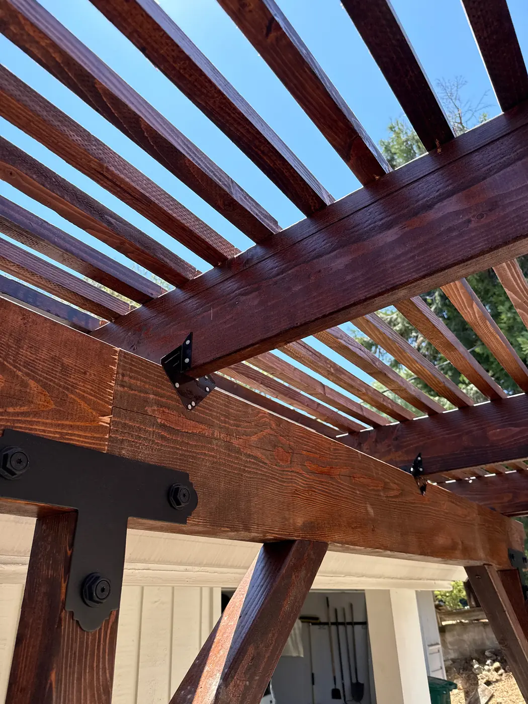 Stained beams and steel brackets of a wood pergola